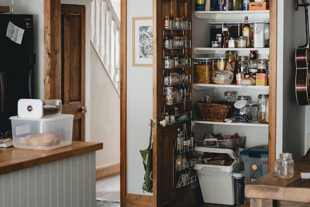 Small pantry filled with different jars and baskets in a kitchen