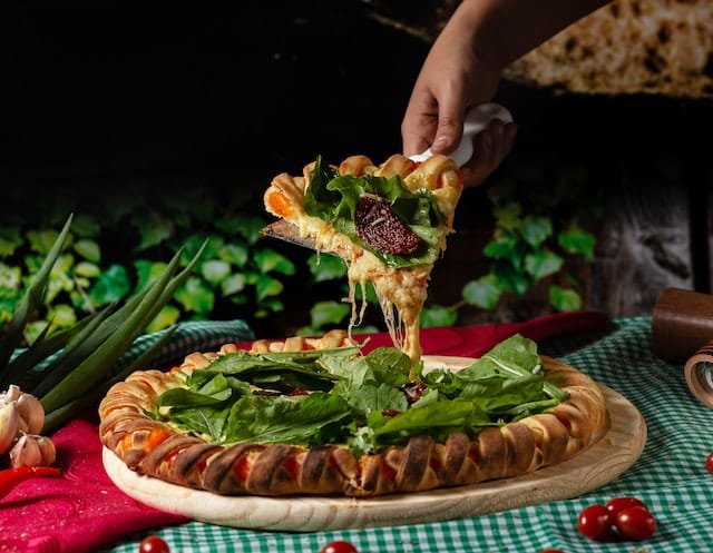 a person grabbing a slice of delicious pizza