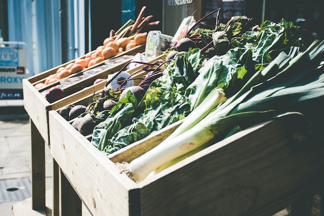 Green leafy vegetables in wooden boxes at a market where many sustainable NYC restaurants get their food.