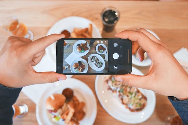 A set of hands taking a picture of restaurant food from our ultimate foodie's guide to Boulder, CO.