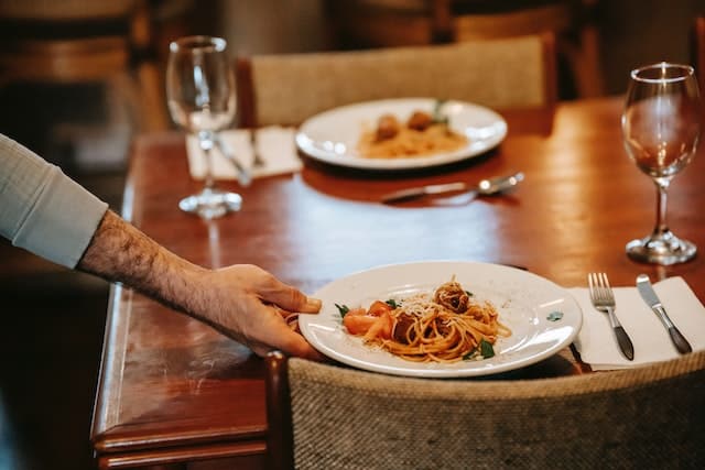 A waiter serving pasta